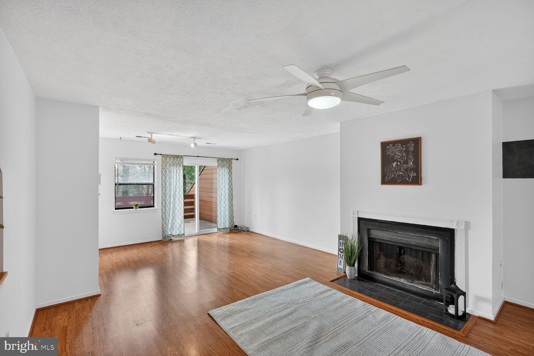7505 Weather Worn Way, Unit E Columbia, MD 21046 - Photo 5 of 32 a view of an empty room with wooden floor fireplace and a window