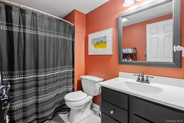 a bathroom with a sink a toilet a mirror and shower curtain