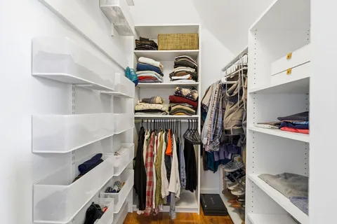 a view of walk in closet with clothes and shoes