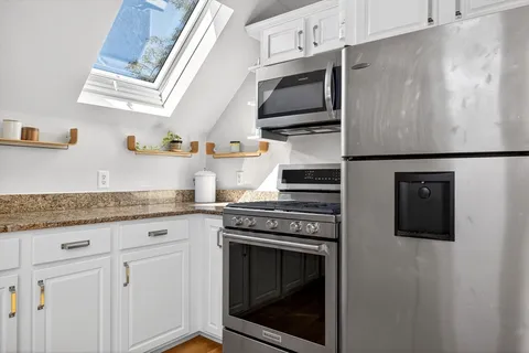 a kitchen with stainless steel appliances granite countertop a stove a microwave and a refrigerator