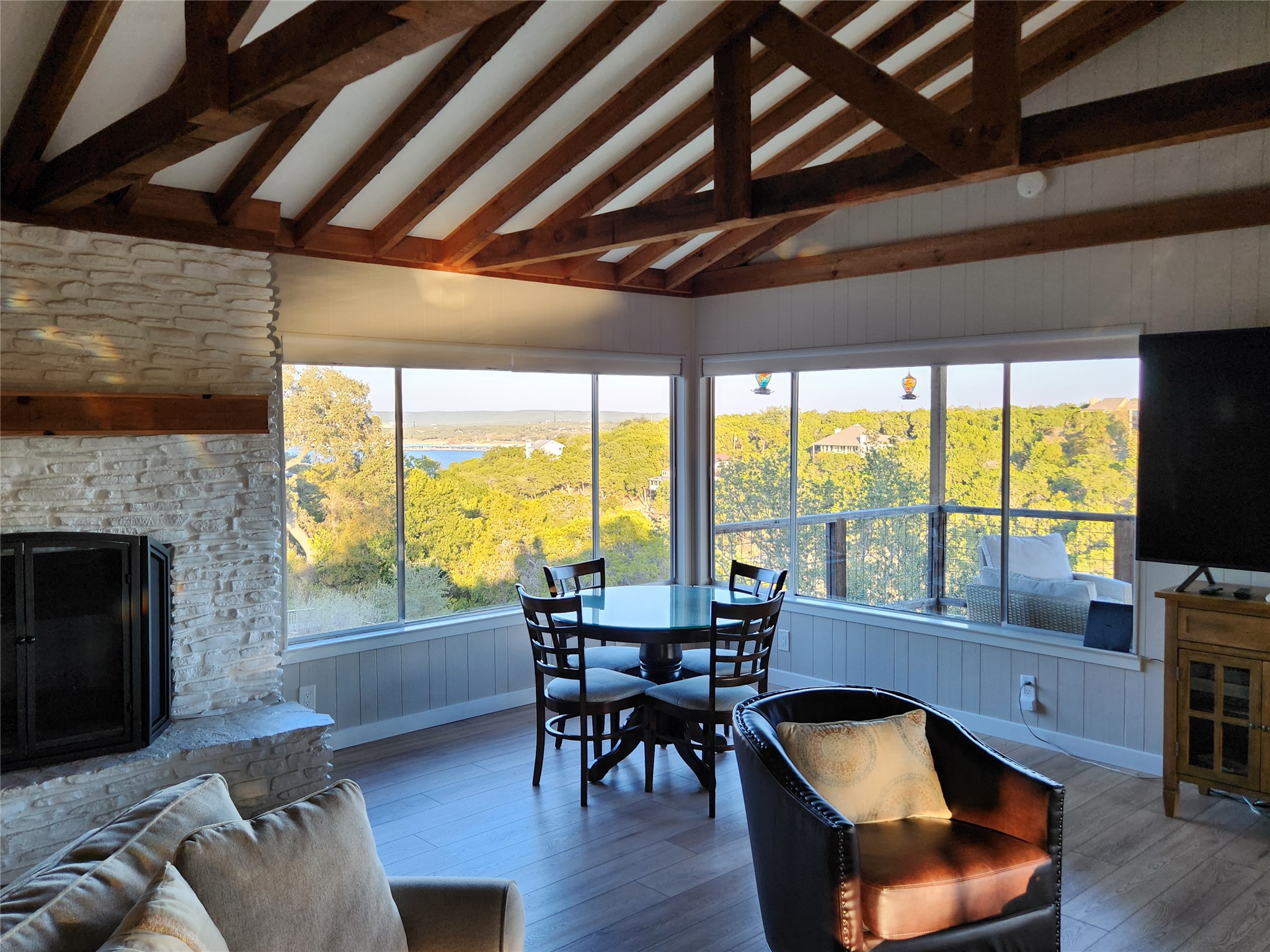 3807 Boat Dock Road Lago Vista, TX 78645 - Photo 5 of 37 A stone fireplace anchors this living space, offering expansive views of the lake and surrounding trees.