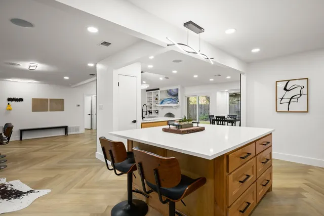 a kitchen with stainless steel appliances granite countertop a sink a stove a refrigerator cabinets and living room view