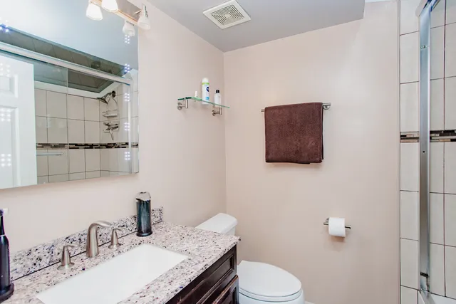 a bathroom with a granite countertop sink a toilet and mirror