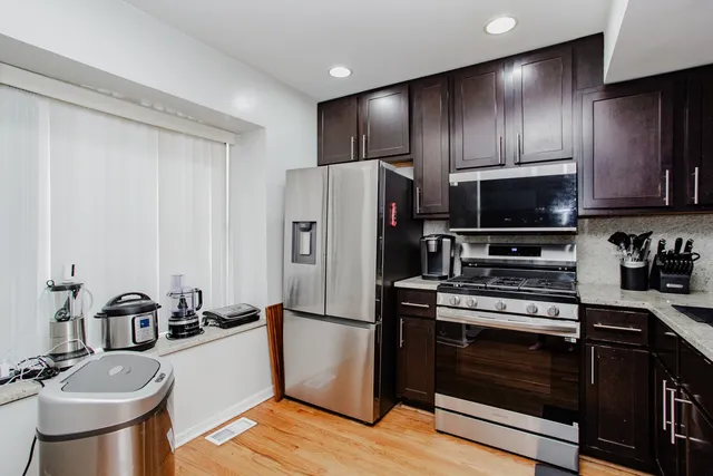 a kitchen with stainless steel appliances granite countertop a refrigerator stove and sink with wooden floor