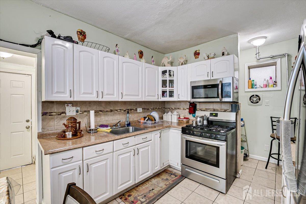 438 Lawrie Street Perth Amboy, NJ 08861 - Photo 20 of 49 a kitchen with stainless steel appliances a white stove top oven and a refrigerator