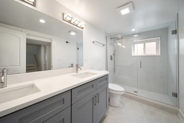 a bathroom with a sink a toilet a shower and a mirror
