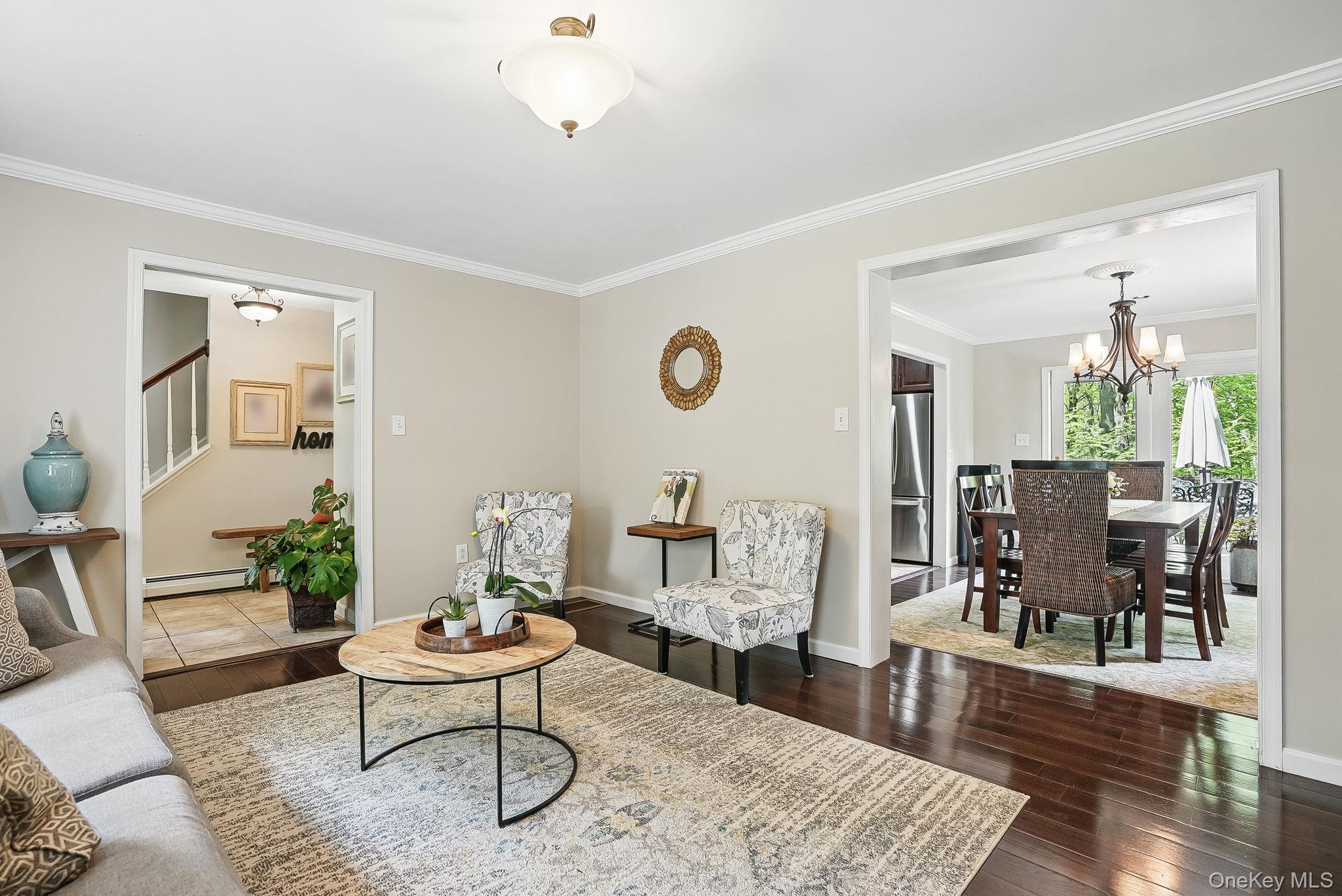 304 Church Road Putnam Valley, NY 10579 - Photo 15 of 50 Living room featuring baseboard heating, a chandelier, crown molding, stairway, and hardwood / wood-style flooring