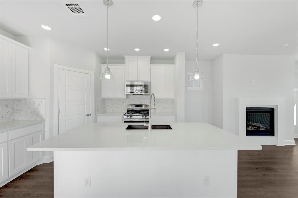 3501 Pineda Way McKinney, TX 75071 - Photo 19 of 40 a large white kitchen with a refrigerator a oven and a fireplace