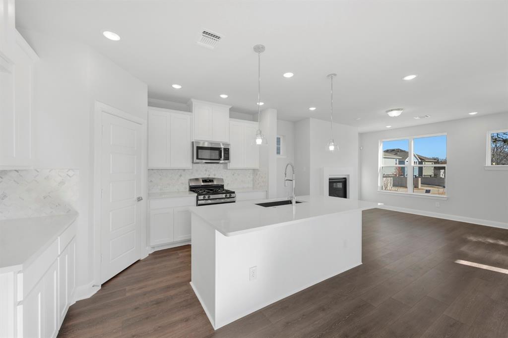 3501 Pineda Way McKinney, TX 75071 - Photo 20 of 40 a large white kitchen with stainless steel appliances kitchen island a stove a refrigerator a center island a stove and a sink