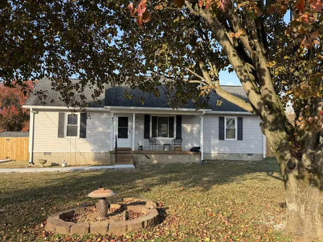 a front view of a house with a yard covered with snow and trees