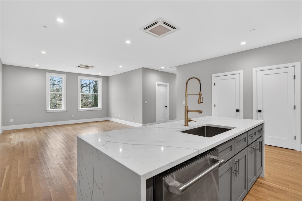 54 River Street, Unit 2 Boston, MA 02126 - Photo 4 of 16 a kitchen with stainless steel appliances granite countertop a sink and dishwasher with wooden floor