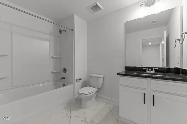 a bathroom with a granite countertop sink a toilet a mirror and a bathtub