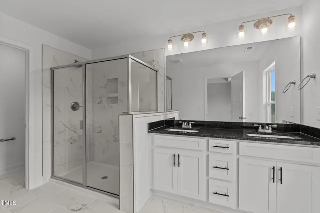 a bathroom with a granite countertop sink two mirror and a shower