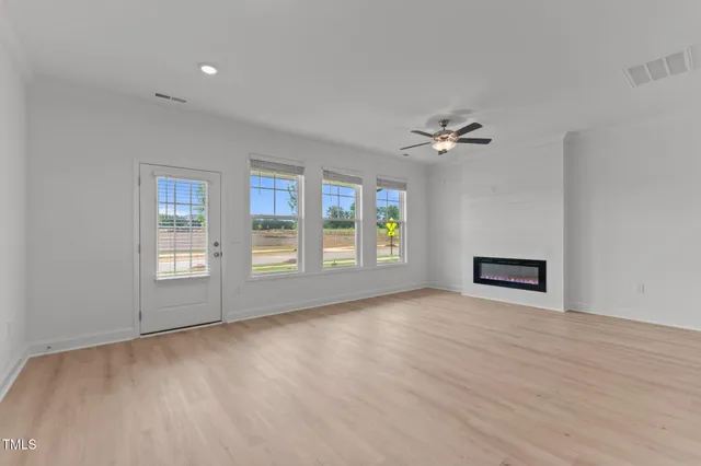 a view of an empty room with a window and wooden floor