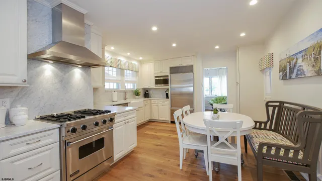 a kitchen with stainless steel appliances a white table chairs and a refrigerator