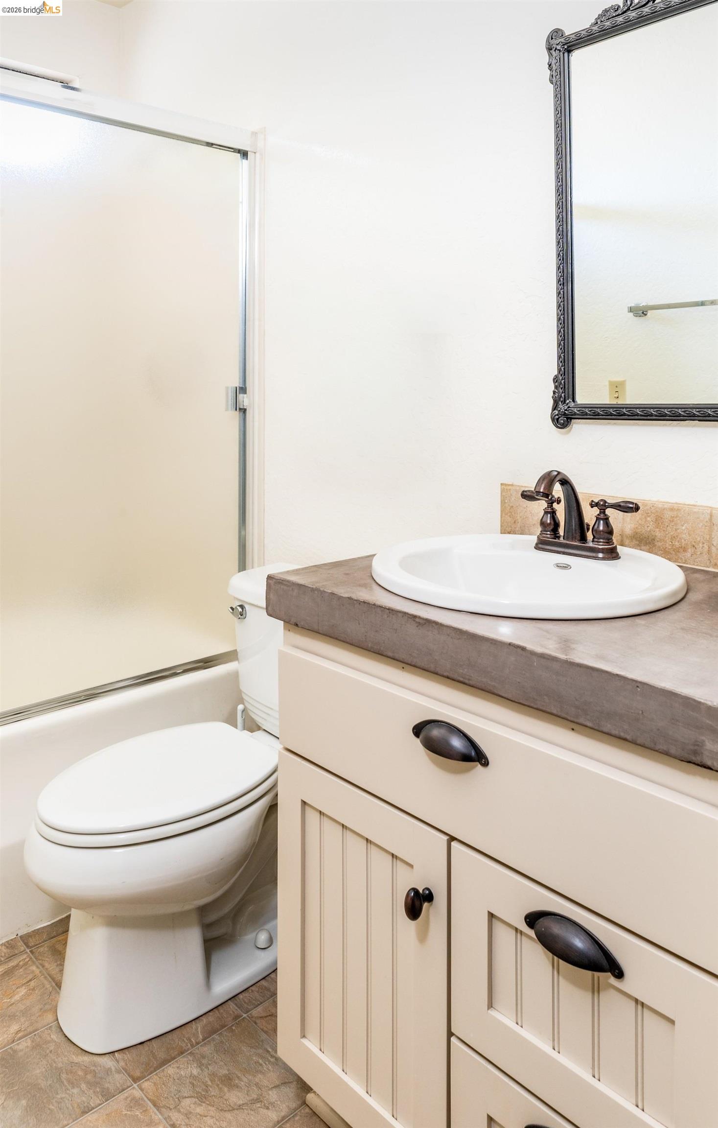 19711 Pleasantview Drive Groveland, CA 95321 - Photo 26 of 39 Bathroom featuring a white vanity with beadboard paneling, a concrete-finish countertop, and bronze hardware