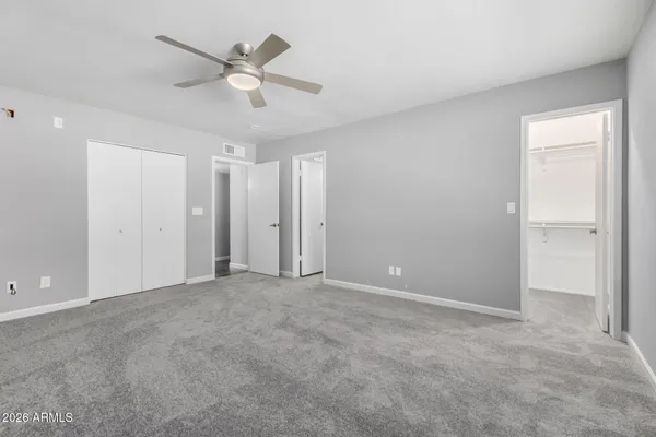 an empty room with closet and ceiling fan