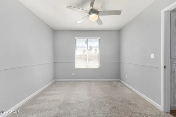 an empty room with a window and a fan