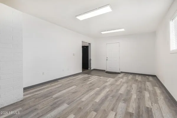 a view of an empty room with wooden floor and a window