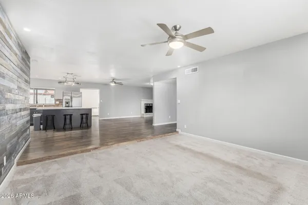 an empty room with chandelier fan and windows
