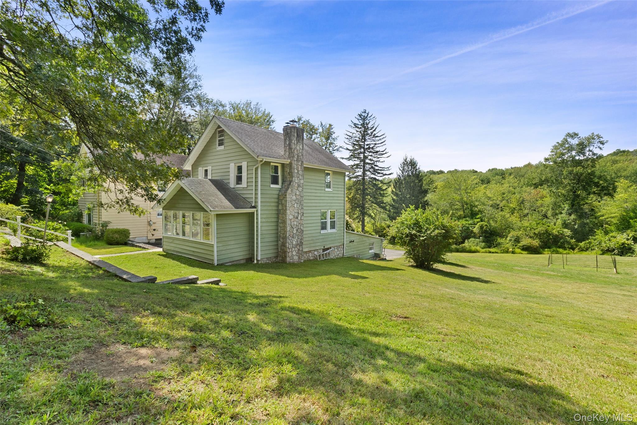 a view of a big house with a big yard and large trees