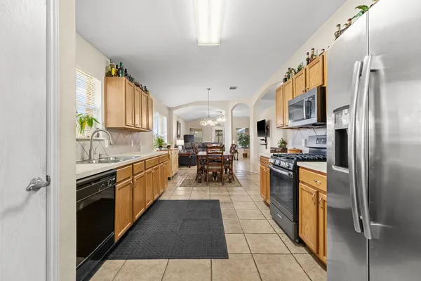 a kitchen with stainless steel appliances granite countertop a refrigerator oven a sink dishwasher and white cabinets with wooden floor