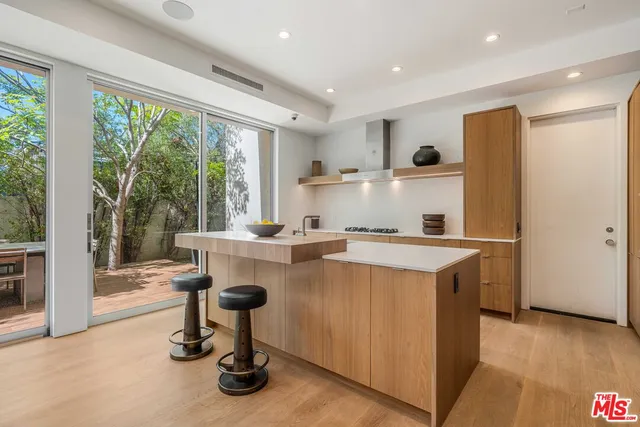 a large kitchen with stainless steel appliances a large counter top a stove and a sink with garden view