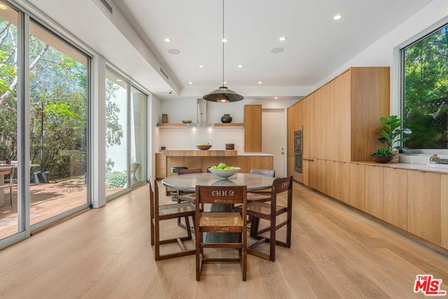 a kitchen with a table chairs wooden cabinets and stainless steel appliances
