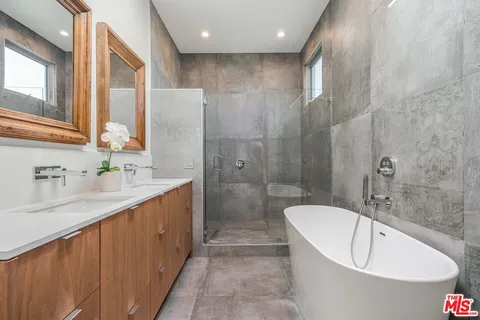 a bathroom with a double vanity sink a toilet a mirror and shower