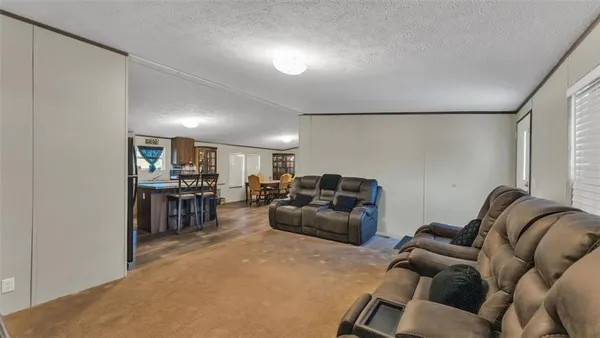 a living room with furniture a kitchen view and a large window