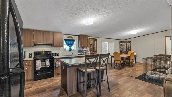 a kitchen with stainless steel appliances granite countertop a stove top oven a sink a dining table and chairs with wooden floor