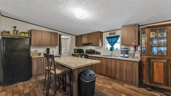 a kitchen with stainless steel appliances granite countertop a refrigerator a sink dishwasher a stove and white countertops with wooden floor