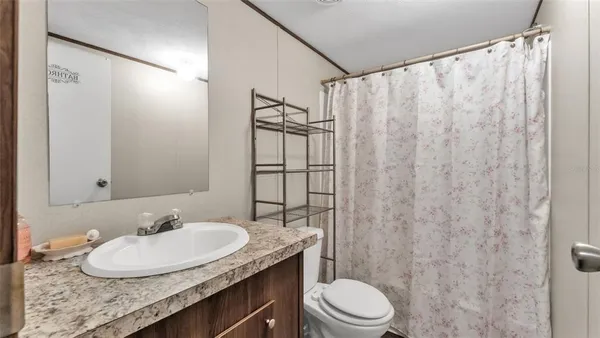 a bathroom with a granite countertop sink toilet and a mirror