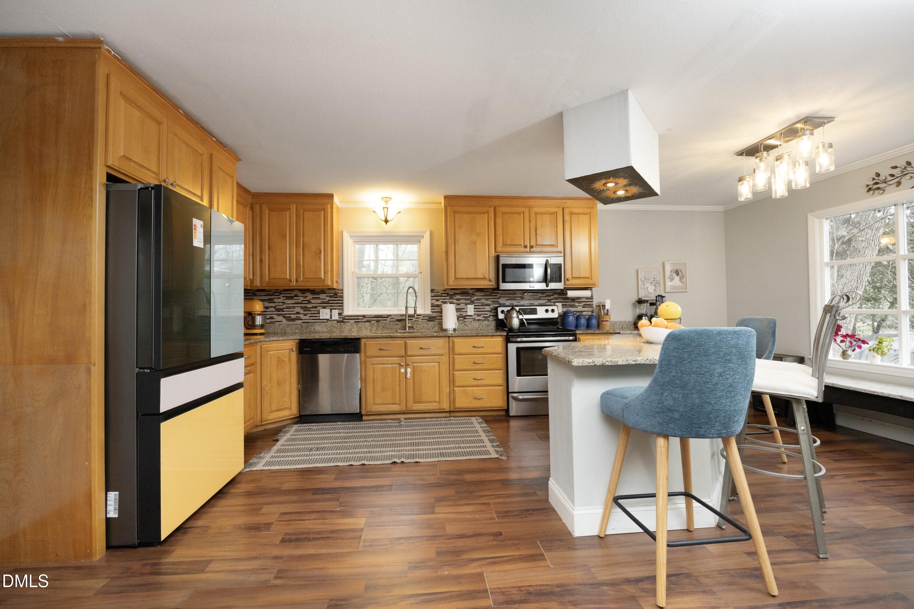 7117 Sunset Lake Road Fuquay-Varina, NC 27526 - Photo 14 of 41 a kitchen with stainless steel appliances granite countertop a refrigerator a stove top oven a sink dishwasher and a dining table with wooden floor