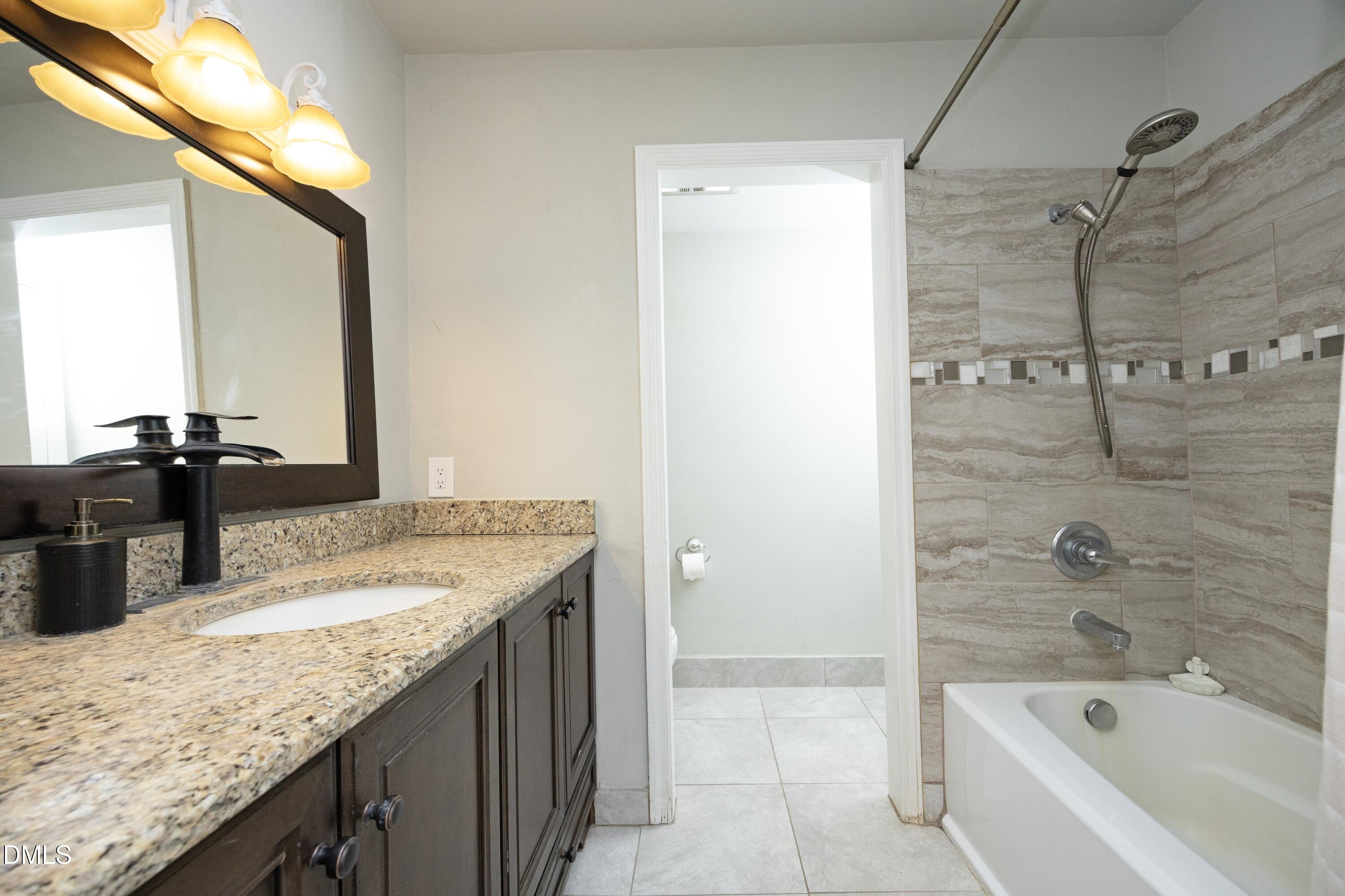 7117 Sunset Lake Road Fuquay-Varina, NC 27526 - Photo 21 of 41 a bathroom with a granite countertop sink a mirror and a bathtub