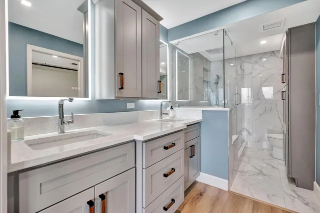 a white toilet sitting next to a bathroom sink and a mirror