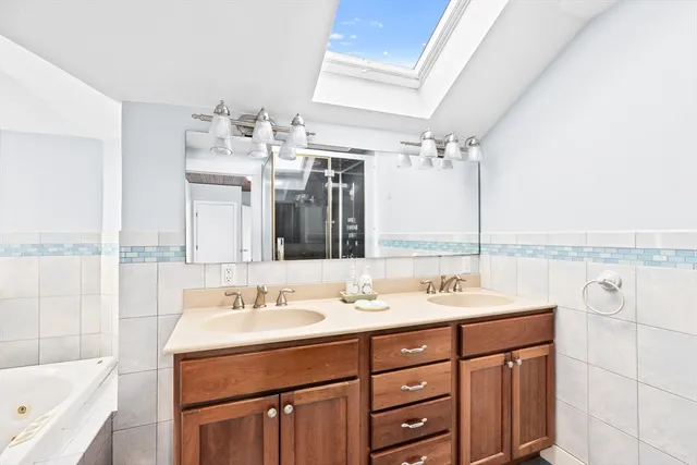 a bathroom with a double vanity sink a mirror and a bathtub