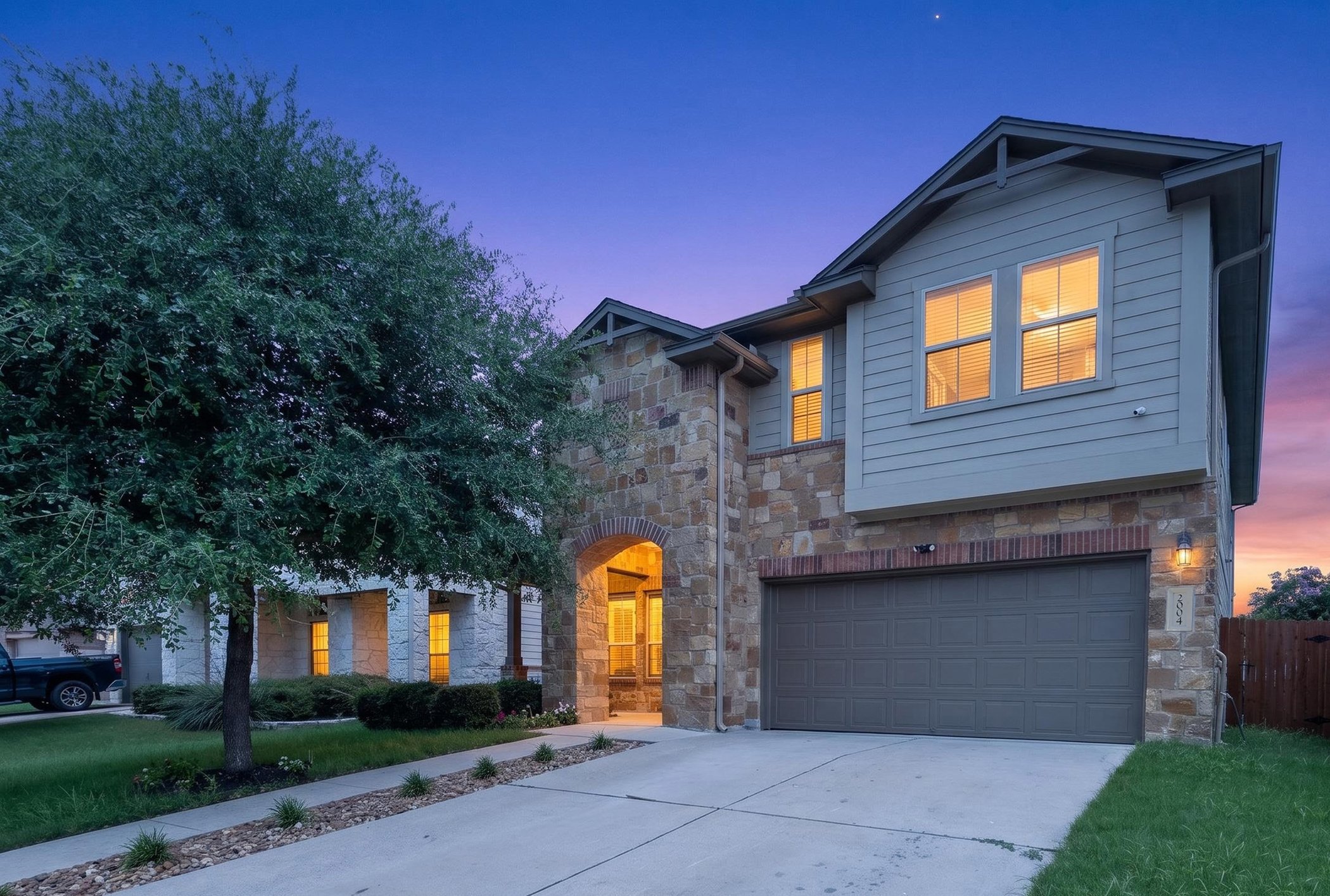 2004 Garretts Way Manchaca, TX 78652 - Photo 2 of 39 Stone and siding create an inviting facade, featuring an integrated garage and charming arched entryway.