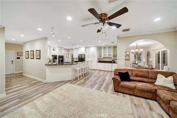 a large white kitchen with granite countertop a stove a sink a dining table and chairs with wooden floor