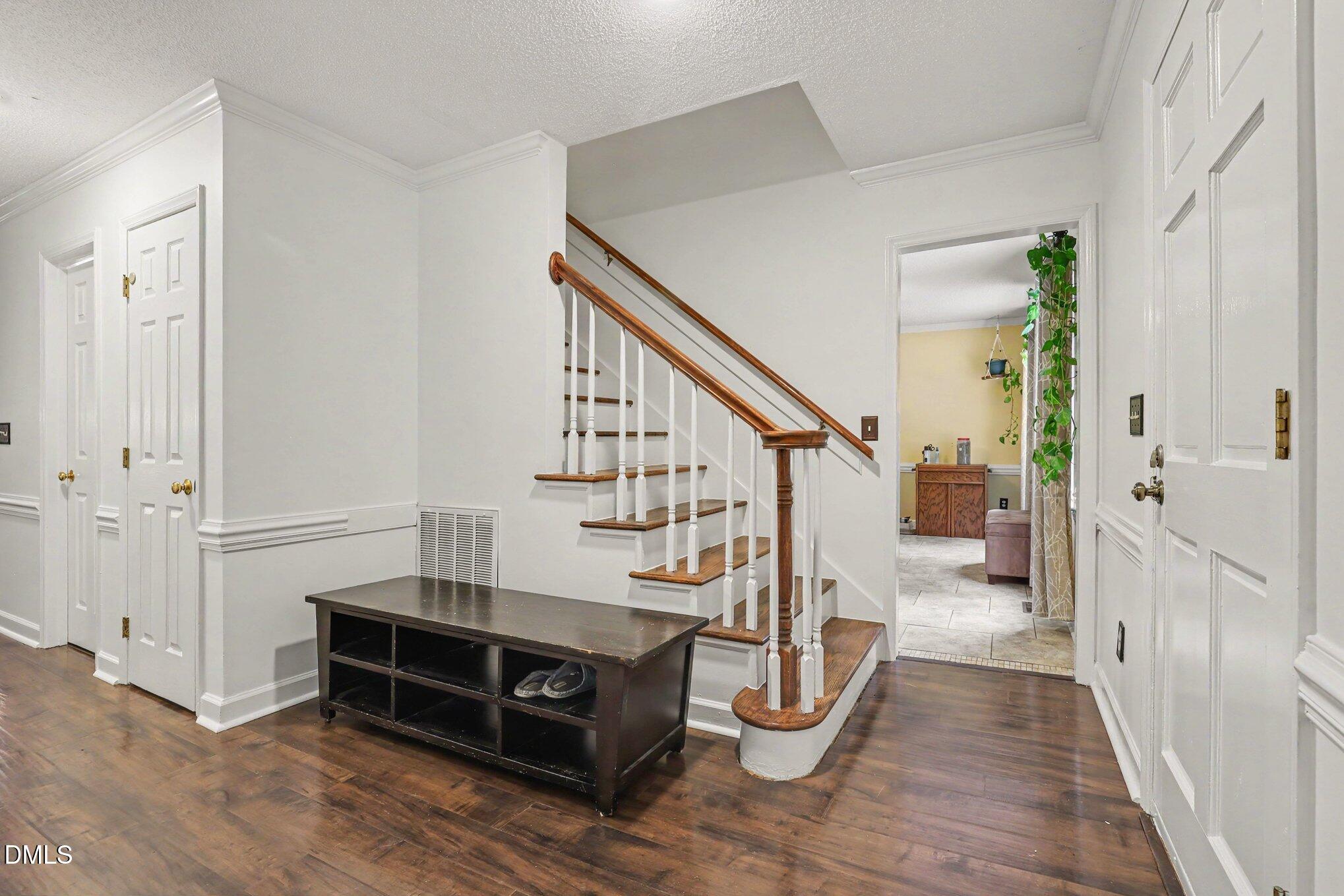 114 Oak Hollow Road Timberlake, NC 27583 - Photo 5 of 31 Foyer featuring wood-finish flooring, white paneled doors with brass hardware, a staircase with white risers and a wood handrail, and white baseboards and crown molding