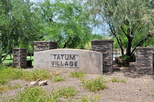 a sign that is sitting in front of a tree