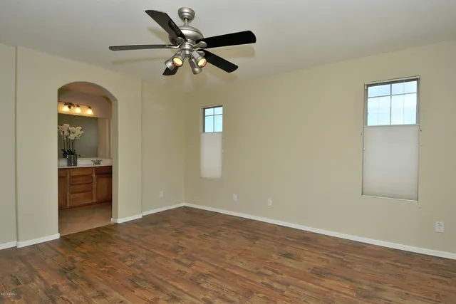 an a view of an empty room with wooden floor and a ceiling fan