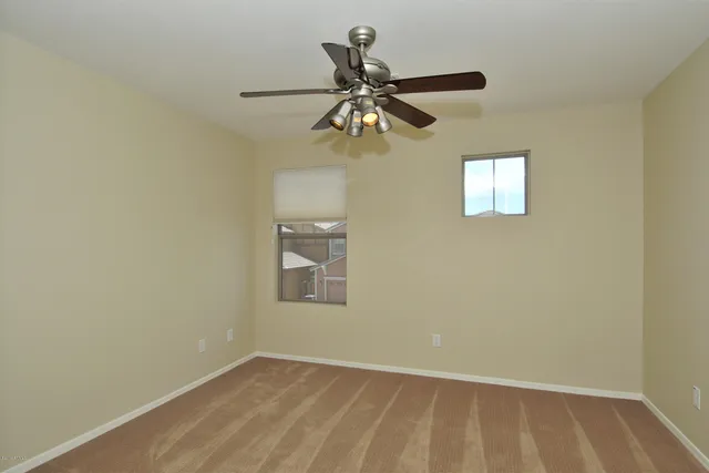 en empty room with fan and a chandelier fan