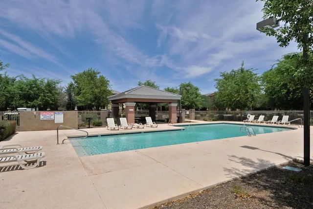 a view of a swimming pool with a bench and lawn chairs