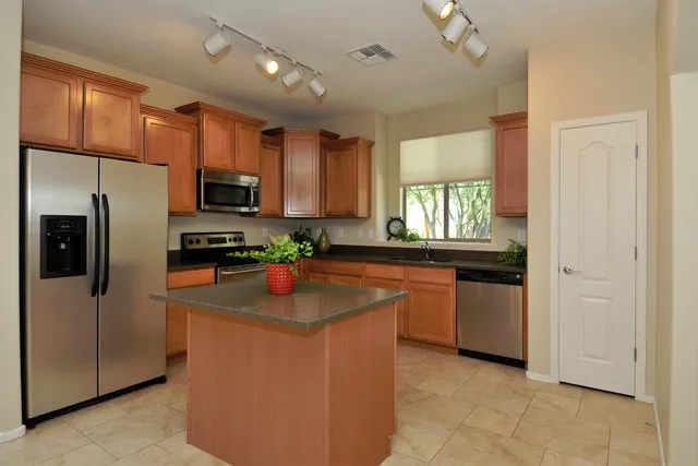 a kitchen with stainless steel appliances granite countertop a sink a stove a refrigerator a center island and cabinets
