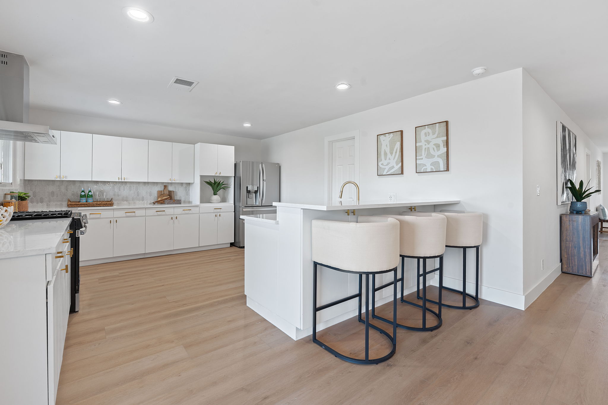 1325 Likeness Road Spicewood, TX 78669 - Photo 15 of 40 Kitchen with a kitchen breakfast bar, white cabinets, stainless steel appliances, light wood-type flooring, and recessed lighting