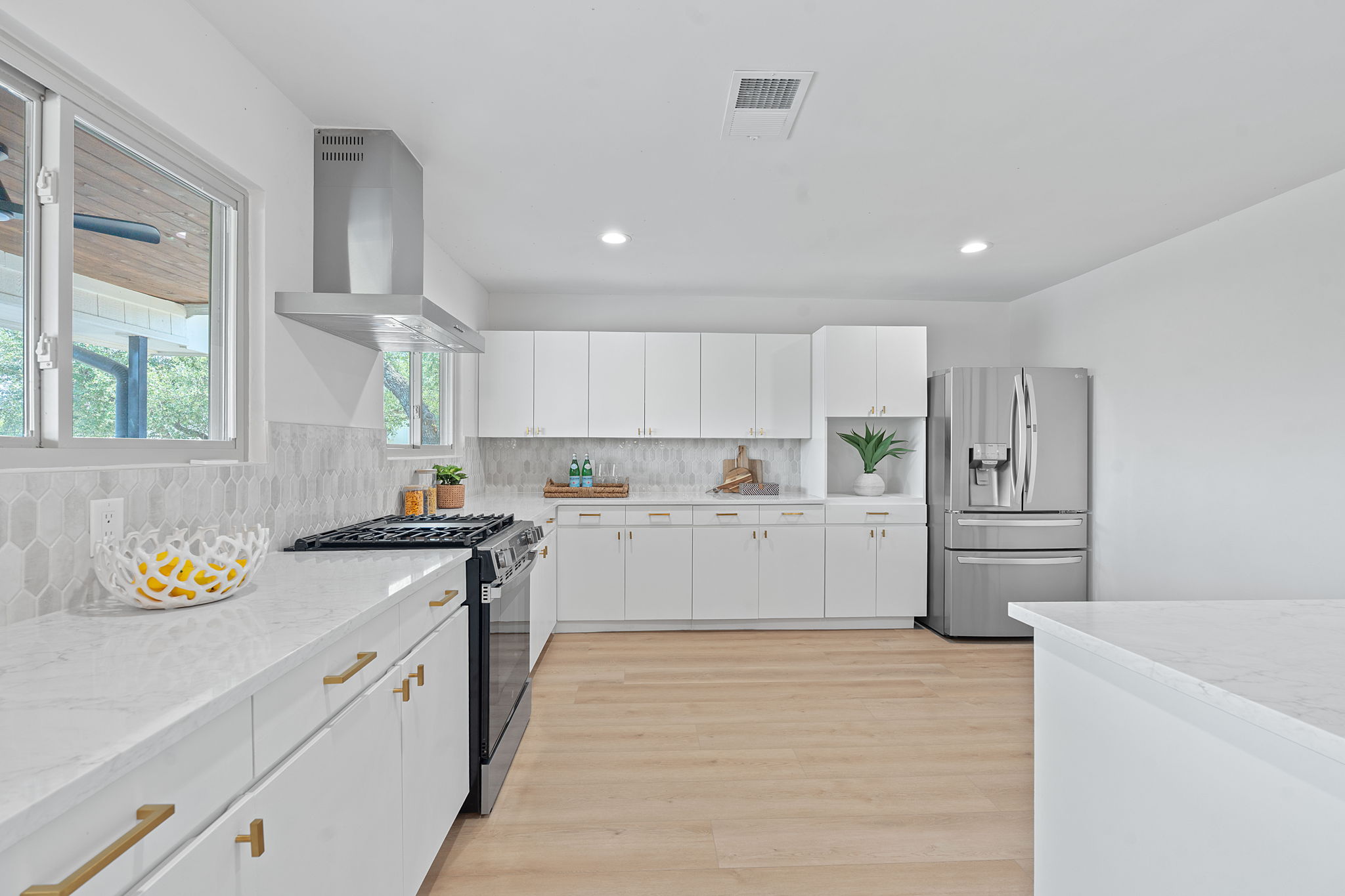 1325 Likeness Road Spicewood, TX 78669 - Photo 16 of 40 Kitchen featuring range with gas cooktop, stainless steel refrigerator with ice dispenser, white cabinets, light wood finished floors, and light stone countertops