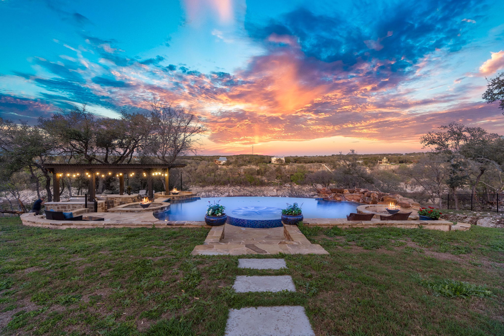 1325 Likeness Road Spicewood, TX 78669 - Photo 2 of 40 View of green lawn with an outdoor fire pit, a patio, and an outdoor pool