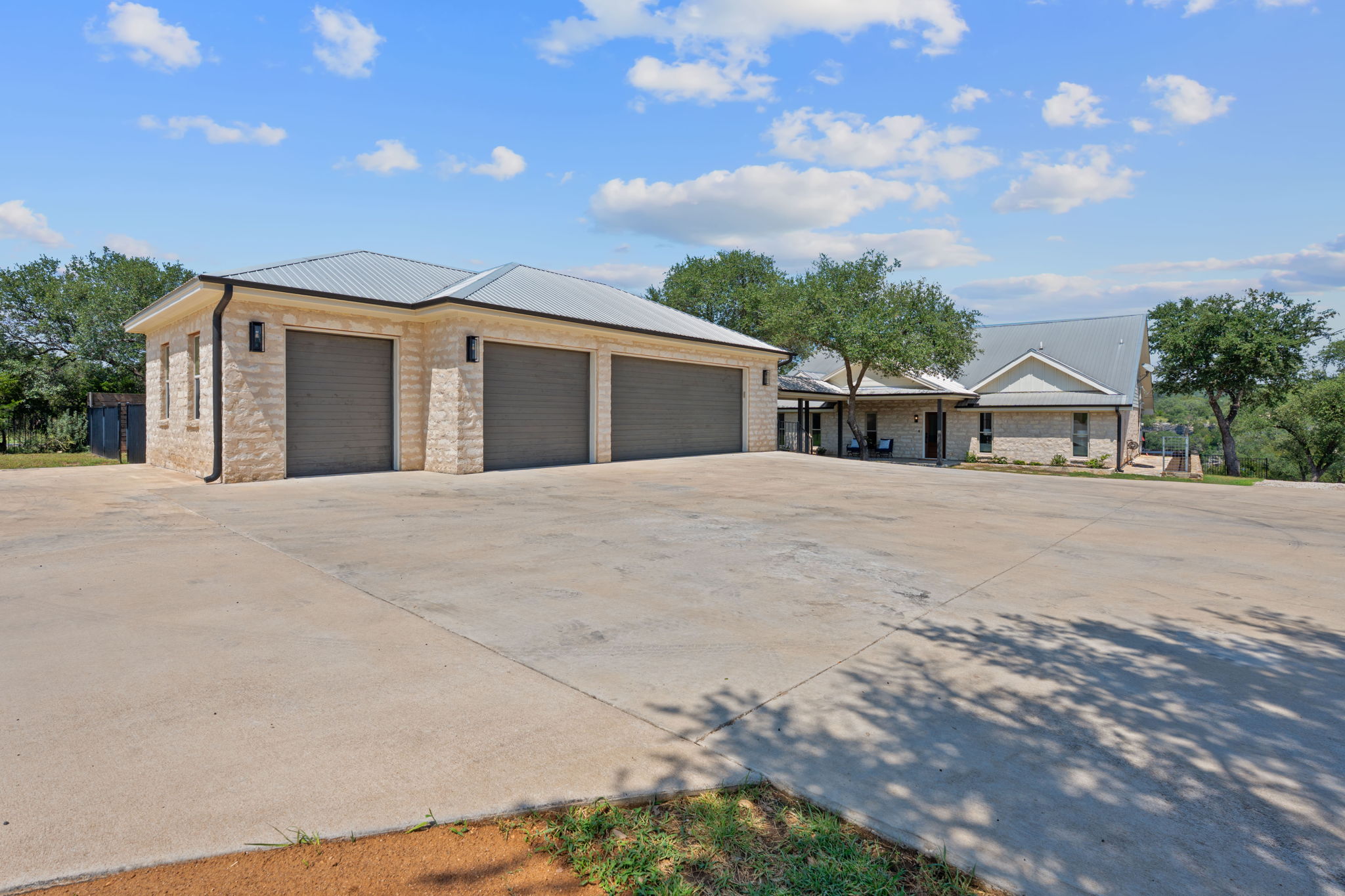1325 Likeness Road Spicewood, TX 78669 - Photo 34 of 40 View of front facade featuring concrete driveway, a garage, and a metal roof