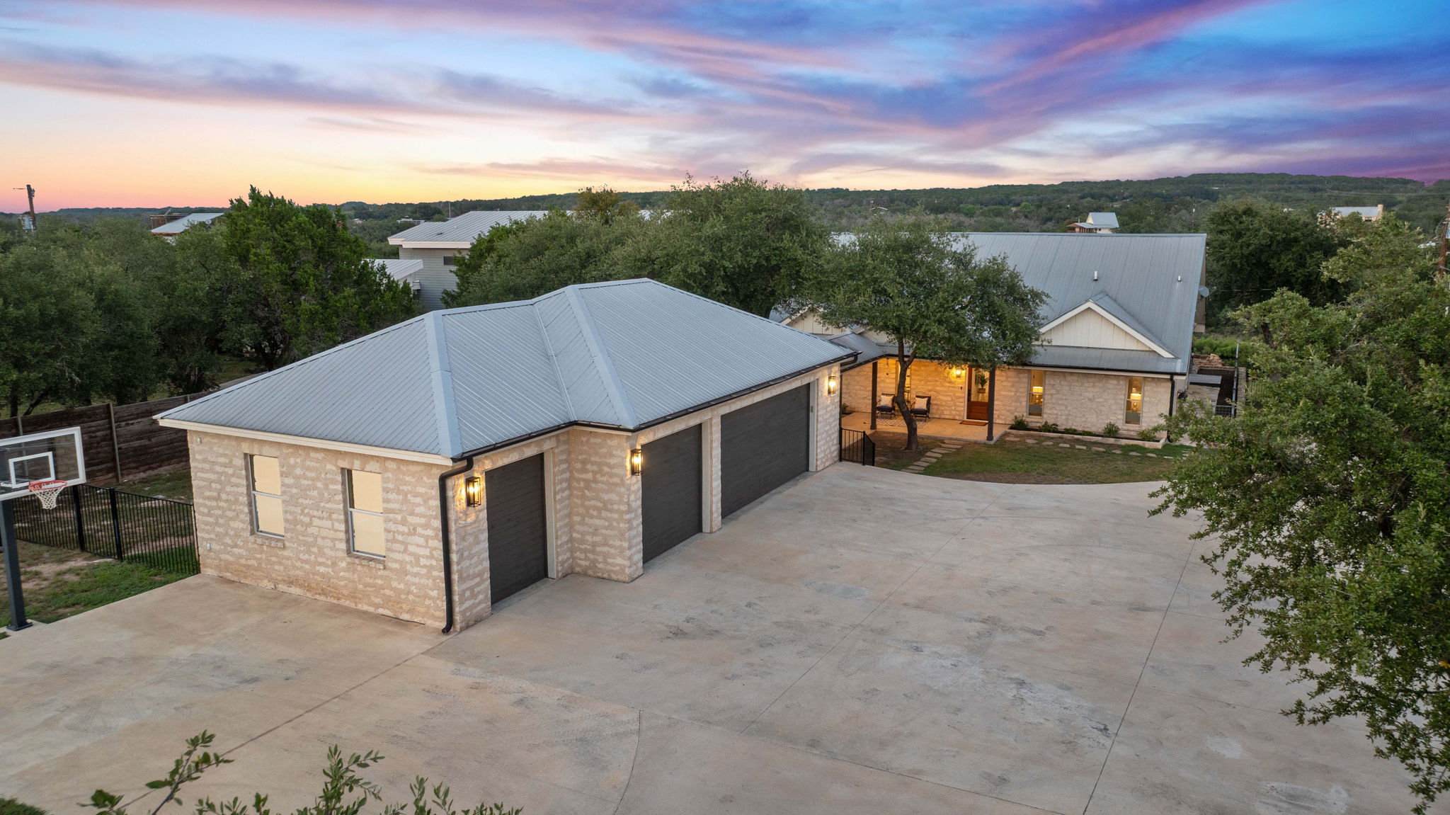 1325 Likeness Road Spicewood, TX 78669 - Photo 35 of 40 View of front facade featuring a metal roof, concrete driveway, brick siding, and a patio